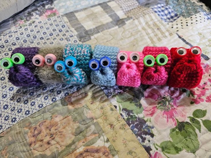 five crocheted owls sitting on top of a bed next to eachother