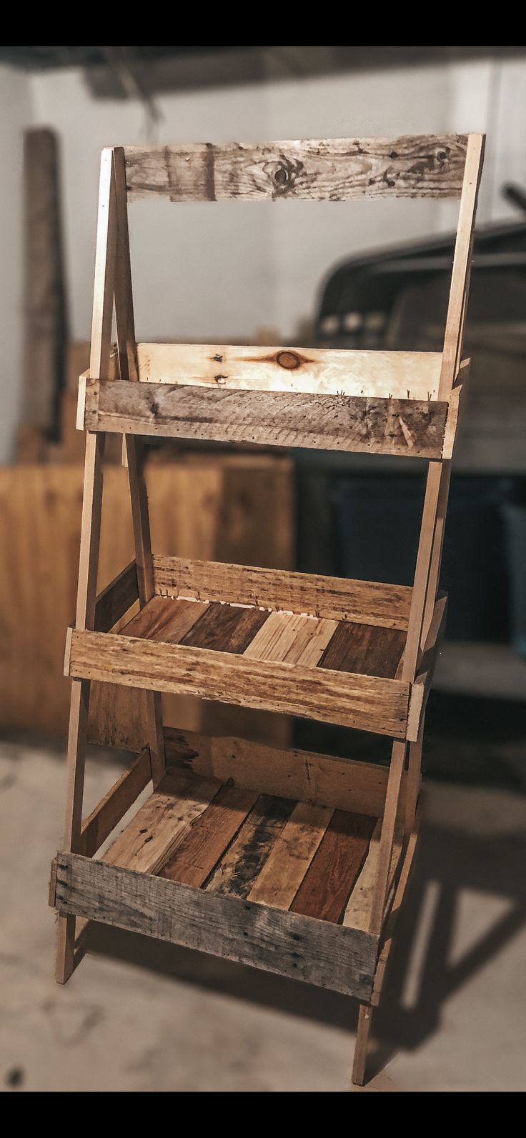 an old wooden ladder is being used as a storage rack for wood pallets in a garage