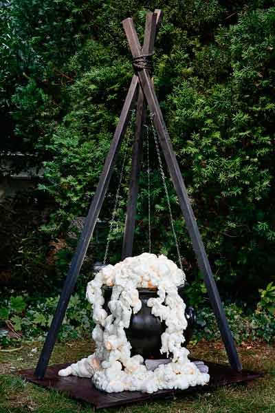 a black vase sitting on top of a wooden stand with white flowers hanging from it's sides