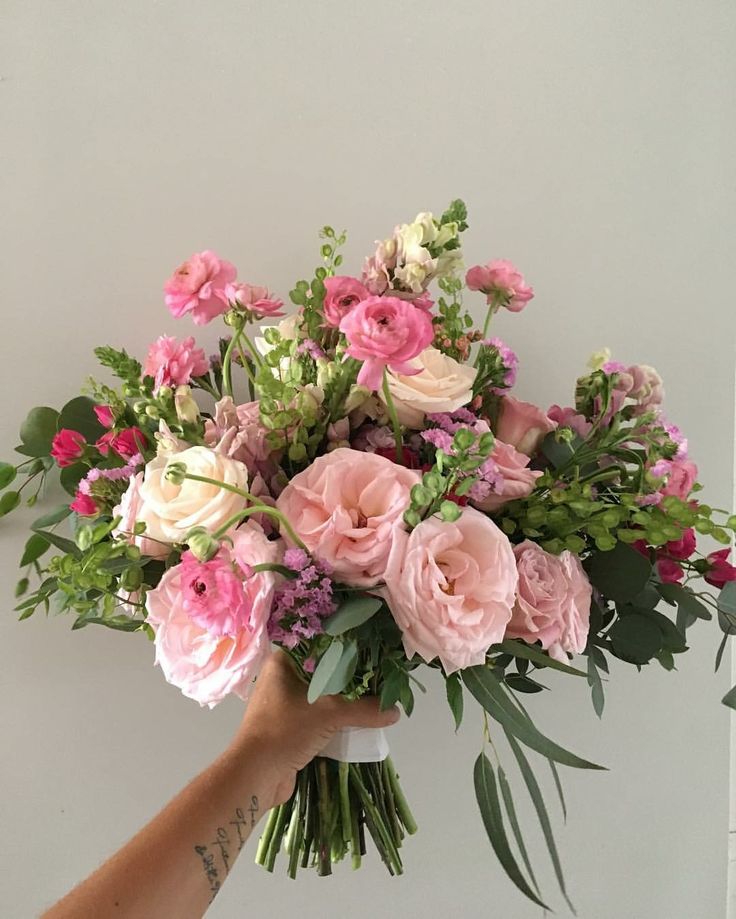 a hand holding a bouquet of pink and white flowers