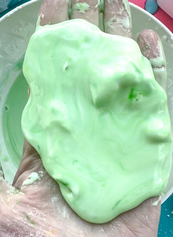 a hand holding a green substance in a white bowl