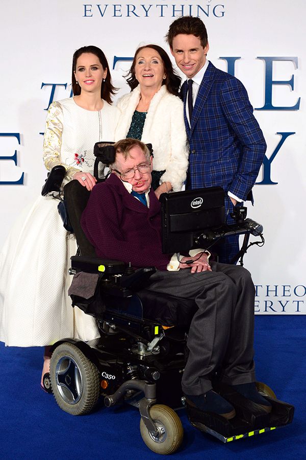 a man in a wheel chair with two women and a man on the blue carpet