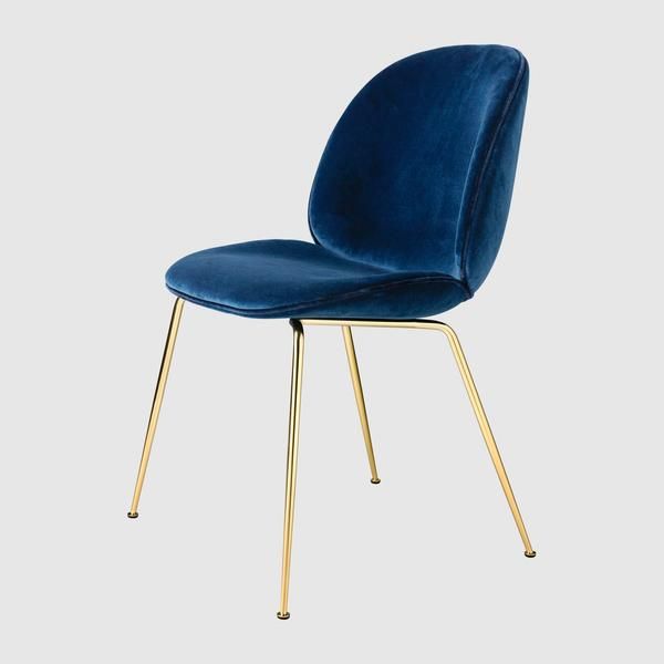 a blue velvet chair with gold legs