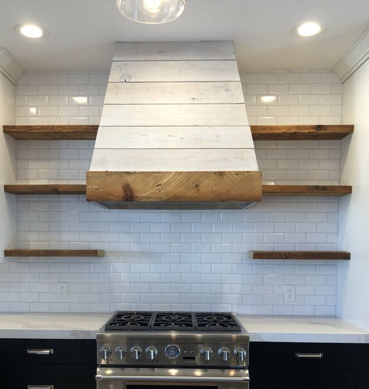 a stove top oven sitting inside of a kitchen next to wooden shelves and open shelving