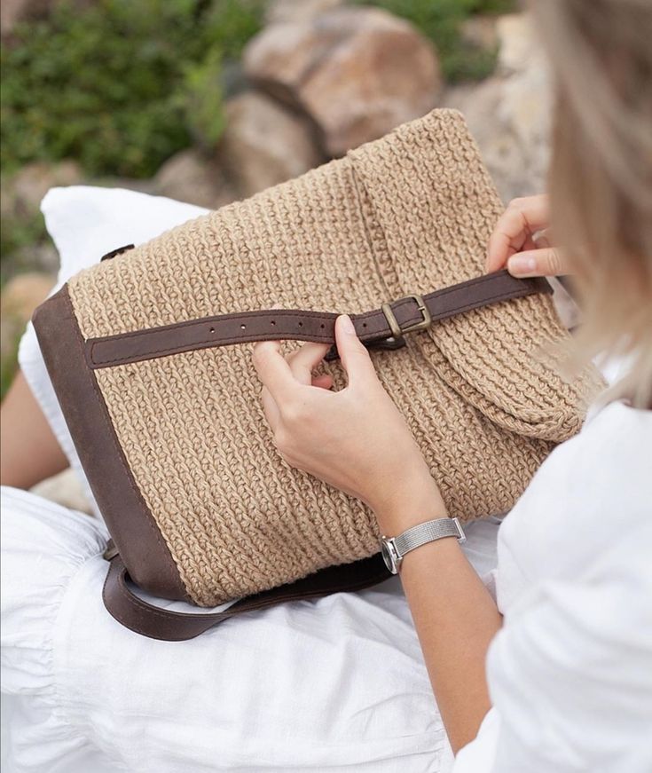 a woman is holding a brown bag on her lap and looking down at the ground