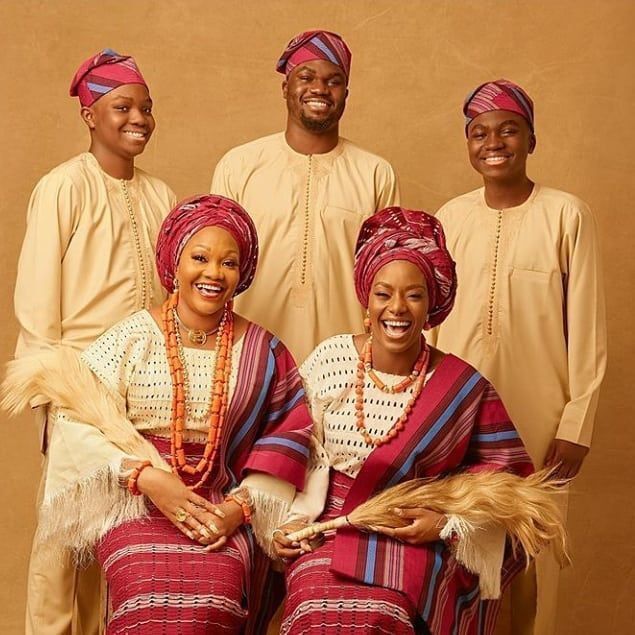 three men and two women dressed in traditional african garb, smiling for the camera