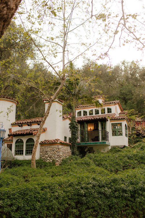 a white house sitting on top of a lush green hillside