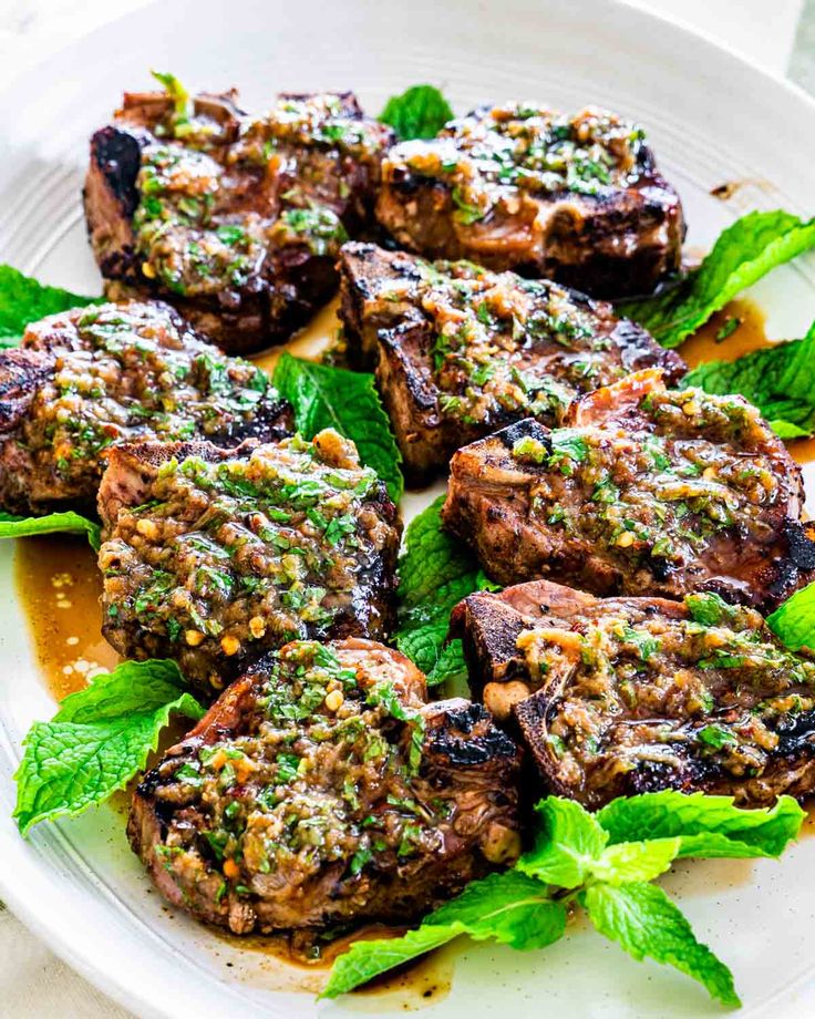 grilled steaks with minty garnish on a white plate, ready to be eaten