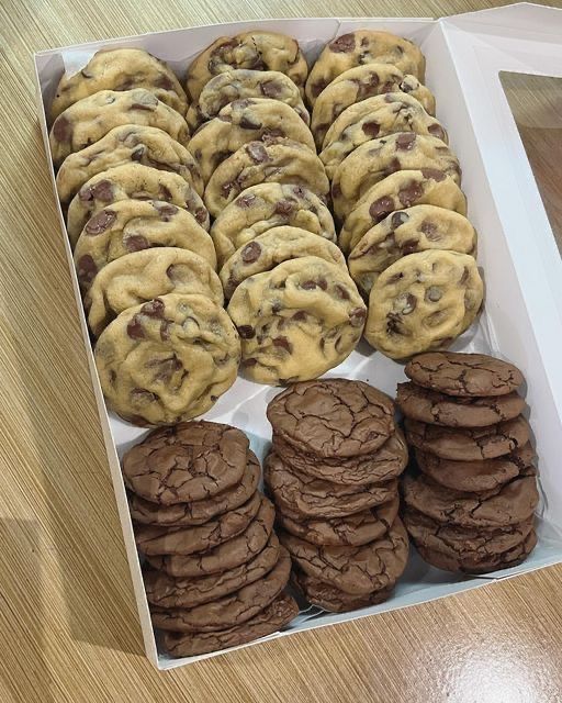 a box filled with chocolate chip cookies on top of a wooden table