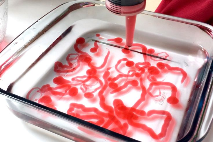 someone is using a red and black blender to make liquid in a glass dish