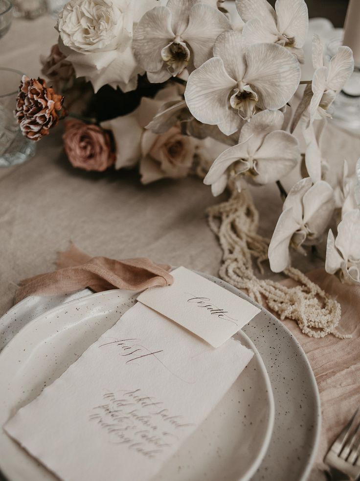 a place setting with white flowers and napkins