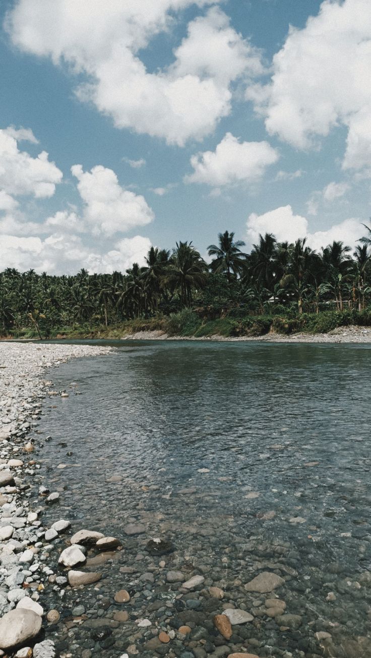 the water is crystal clear and there are rocks on the shore in front of it