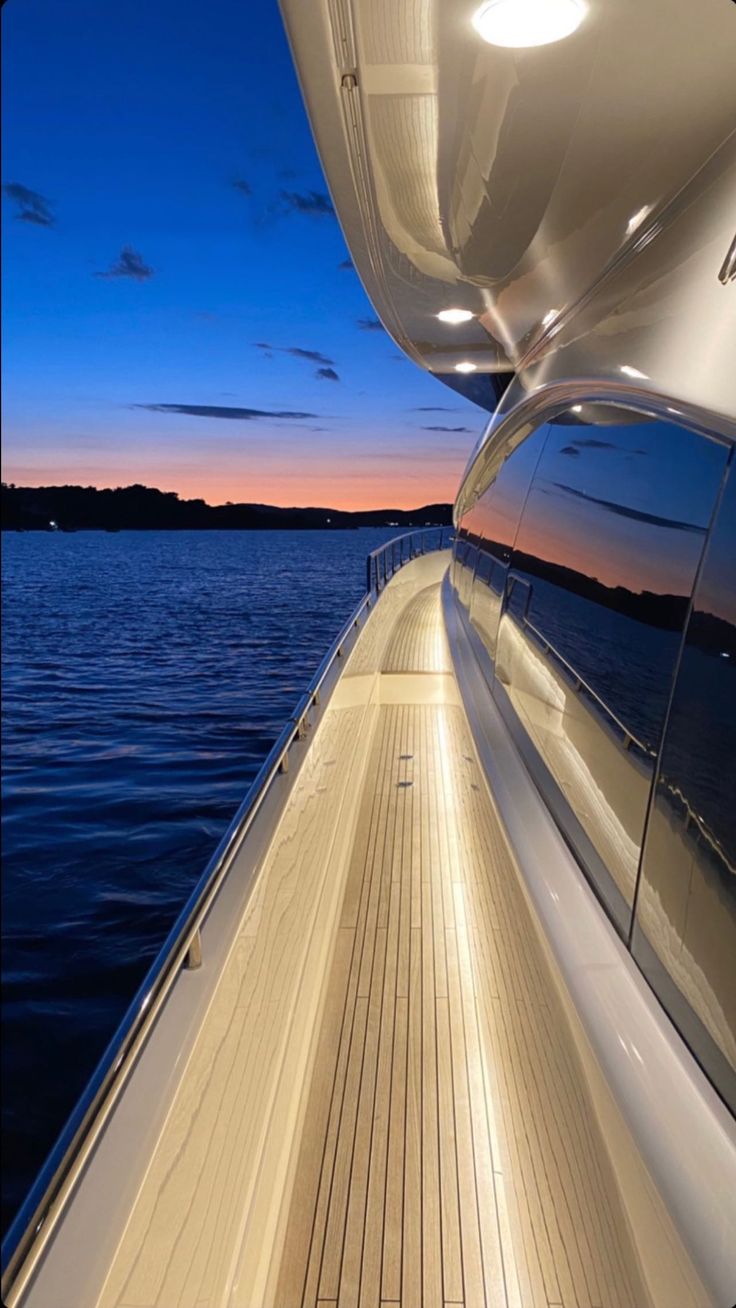 the back end of a boat at night with its lights on and water in the background