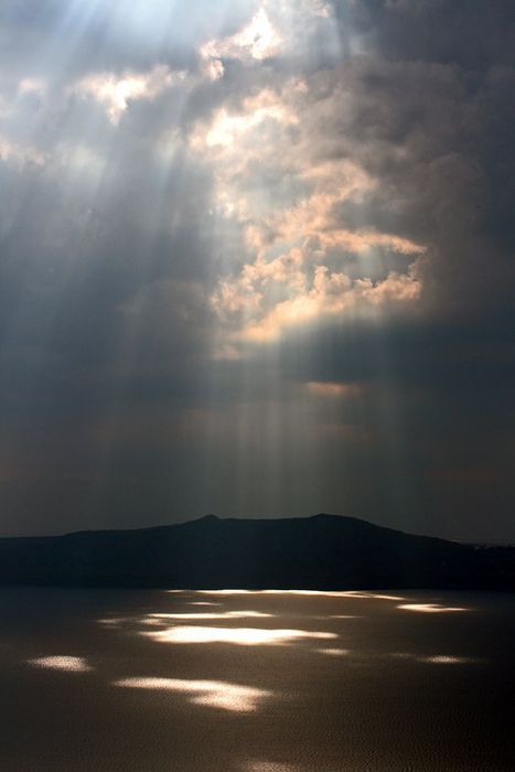 the sun shines through clouds over water