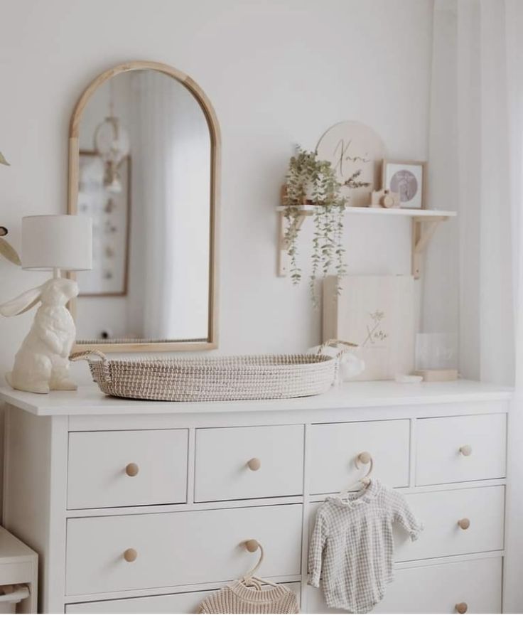 a baby's room with white dresser and mirror