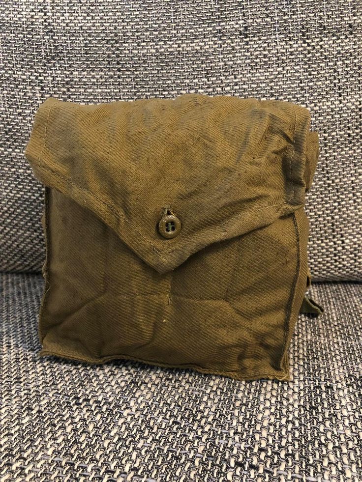 a brown bag sitting on top of a couch next to a pillow with buttons in it