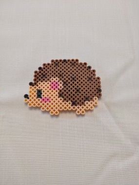 a piece of art made out of perler beads on a white cloth with an animal