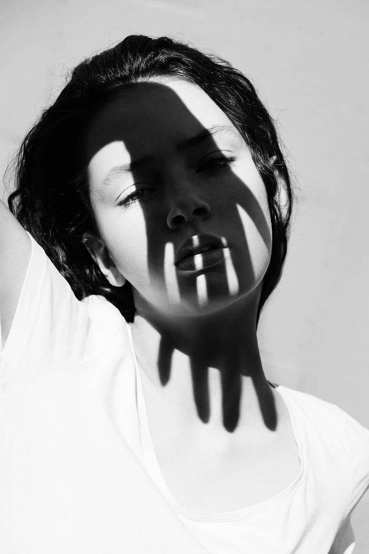 a woman with her face painted like a hand and shadow on the wall behind her