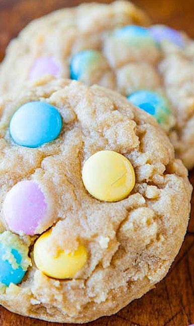 two cookies with m & m's on top are sitting on a wooden table