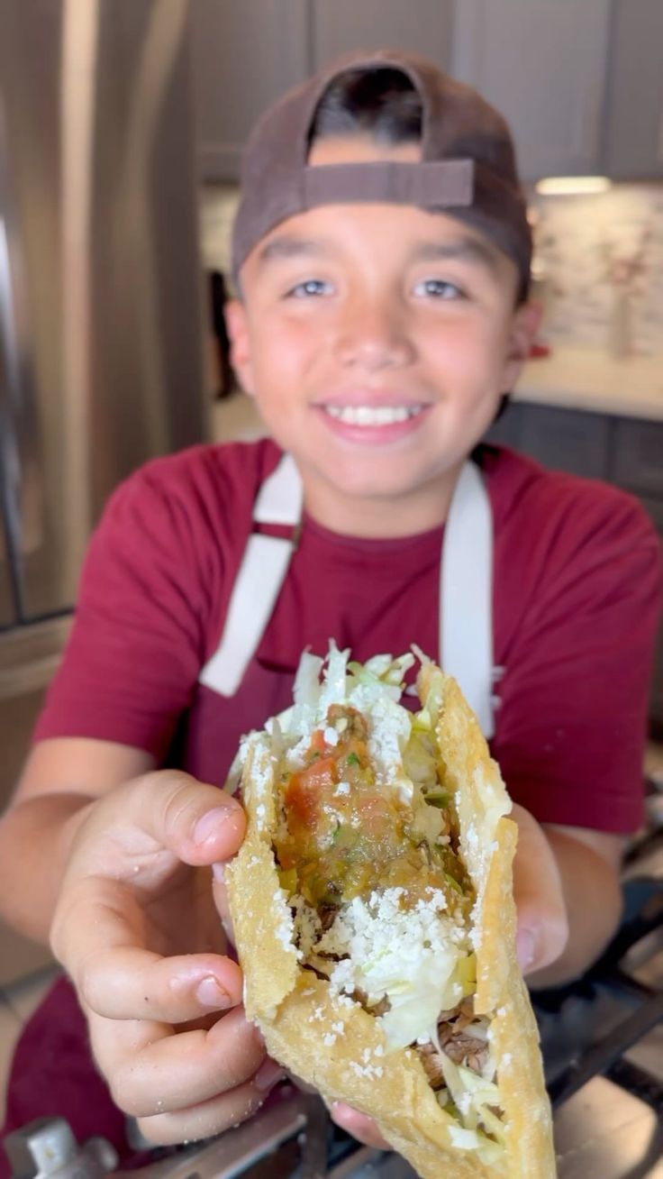 a little boy that is holding some food in his hand and smiling at the camera