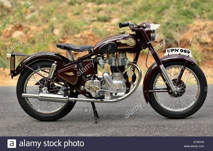 an old motorcycle is parked on the side of the road with grass in the background