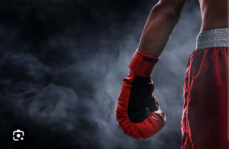 a close up of a person wearing boxing gloves and holding a punching mitt in their right hand