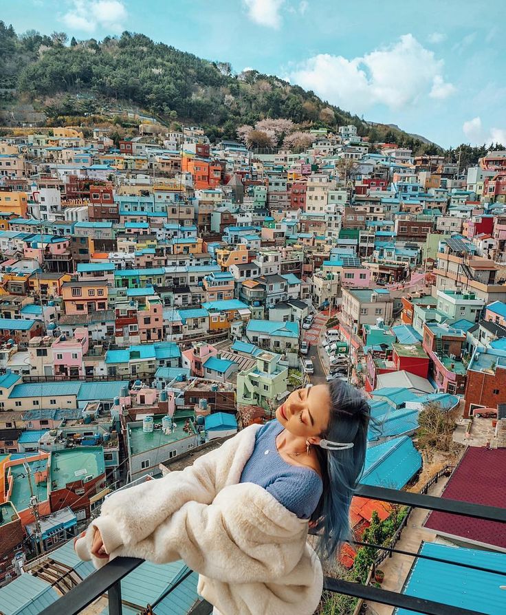 a woman taking a selfie in front of a colorful city with lots of buildings