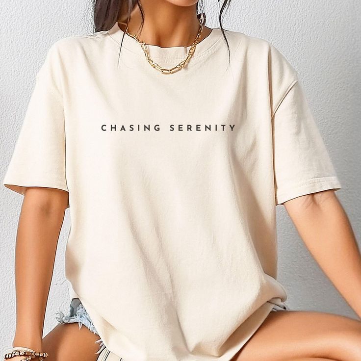 Chasing Serenity Minimalist Cotton T-shirt. Made With Love & Purpose. There's nothing better than a shirt that makes you feel comfortable and stylish at the same time. Style this inspirational tee with a skirt, jeans or leggings, add a piece of jewelry, put on your favorite shoes and you're ready to go make memories. This tee makes a perfect gift for your loved ones.  GENERAL INFORMATION - Comfort Colors® 1717 T-Shirt - Unisex Adult Sizing - Rolled Sleeves in pictures is for styling purposes  on Minimalist Short Sleeve Letter Print T-shirt, Minimalist Letter Print T-shirt For Everyday, Minimalist Graphic Print Short Sleeve Tops, Minimalist Letter Print T-shirt, Minimalist Relaxed Fit Top With Letter Print, Minimalist Streetwear T-shirt, Everyday Beige Tops With Letter Print, Beige Letter Print Top For Everyday, Minimalist Tops With Letter Print And Relaxed Fit