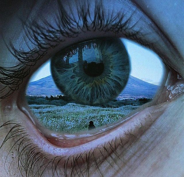 an eye looking into the distance with mountains in the background