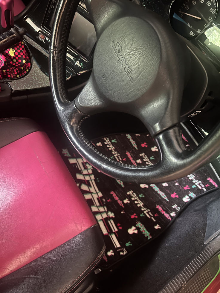 the interior of a car with pink and black leather upholstered seats, steering wheel