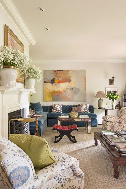 a living room filled with furniture and a painting on the wall above it's fireplace