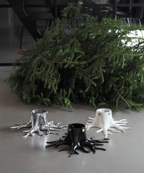 two cups are sitting on the floor next to some tree branches and one is made out of metal