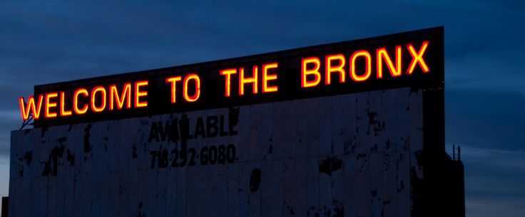 a welcome to the bronx sign is lit up at night with red lights on it