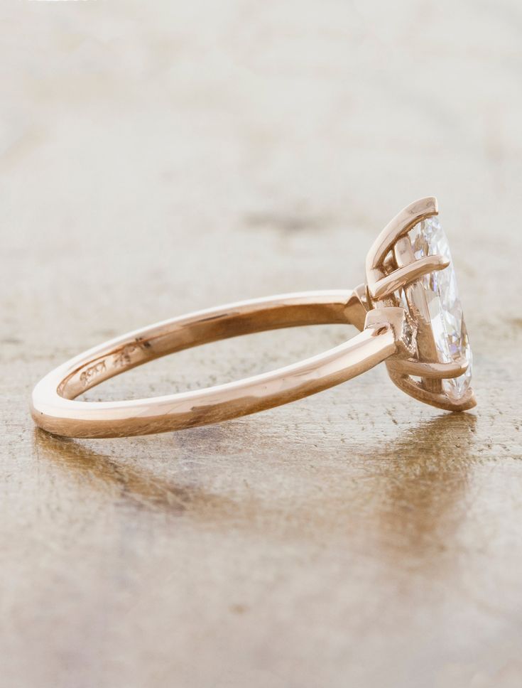 an engagement ring with a pear shaped diamond in the center, on top of a table