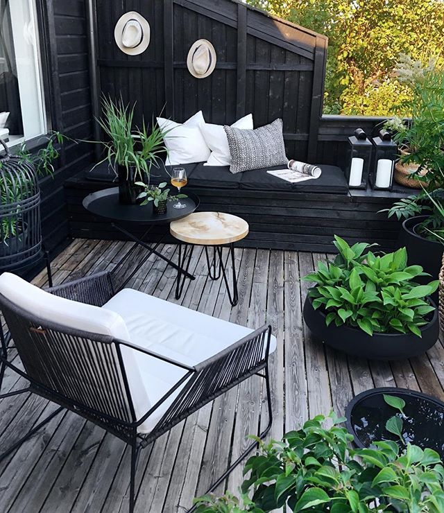 an outdoor deck with chairs, tables and potted plants