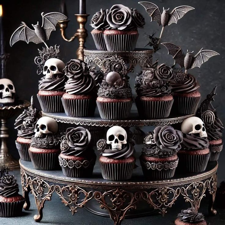 cupcakes decorated with black icing and skulls are displayed on a cake stand