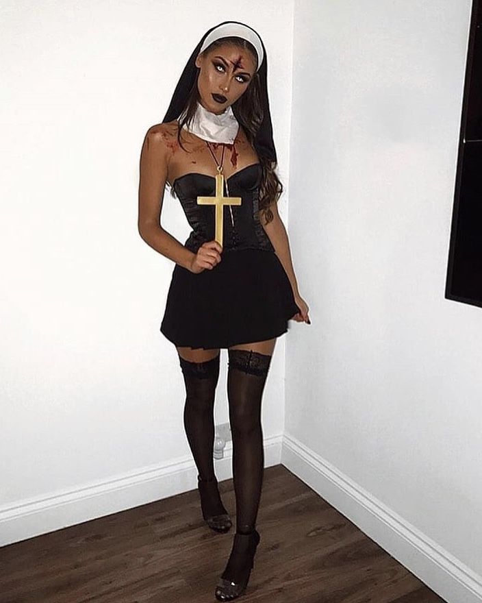 a woman dressed up as a nun holding a cross in her hand and wearing black stockings