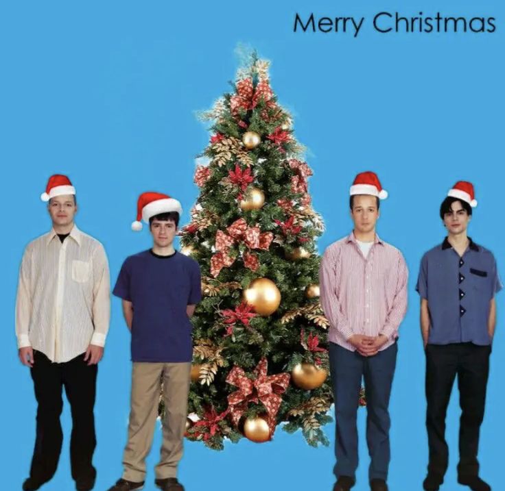 three men standing in front of a christmas tree with hats on their heads and the words merry christmas written below them