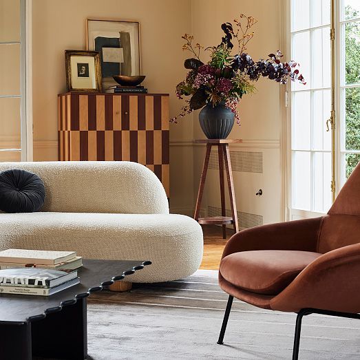 a living room filled with furniture and a vase full of flowers on top of a table