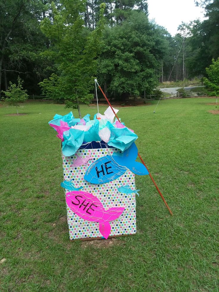 a cardboard box with some writing on it in the middle of a grassy area next to trees