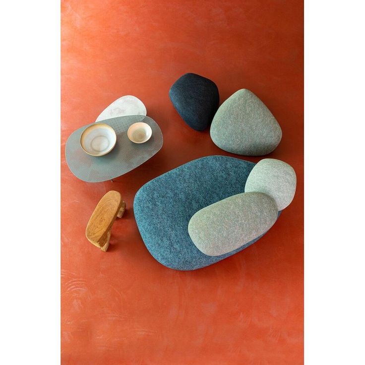 three different colored rocks sitting on top of an orange floor next to a cup and saucer