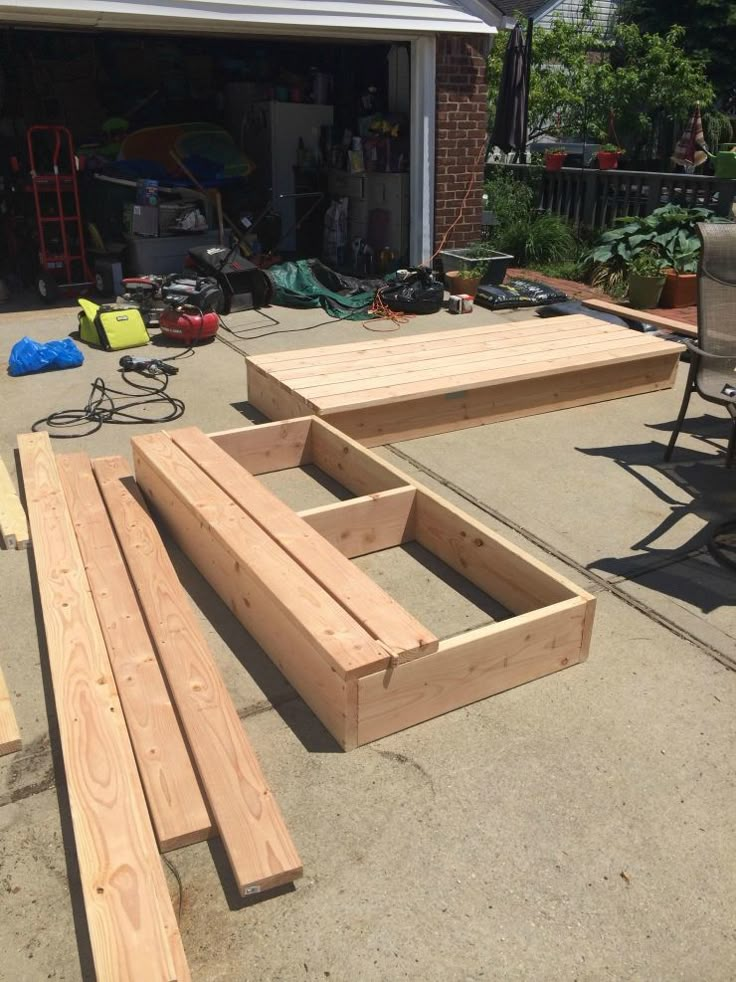 several pieces of wood sitting on the ground in front of a garage with chairs and tables