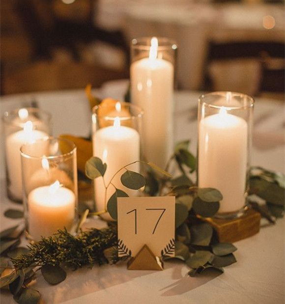 a table with candles and greenery on it