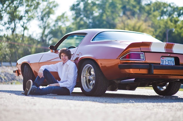 a man sitting on the ground next to a car