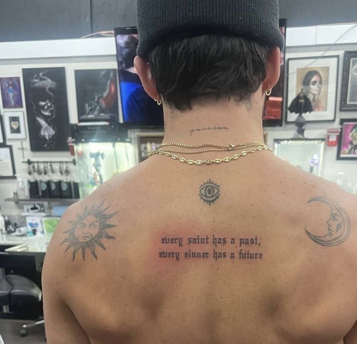 the back of a man's neck with tattoos on it and an inscription above his left shoulder