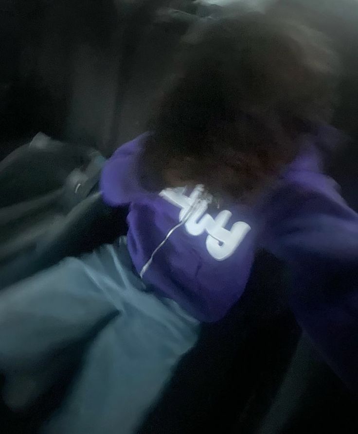 a blurry photo of a person sitting in the back seat of a car with headphones on