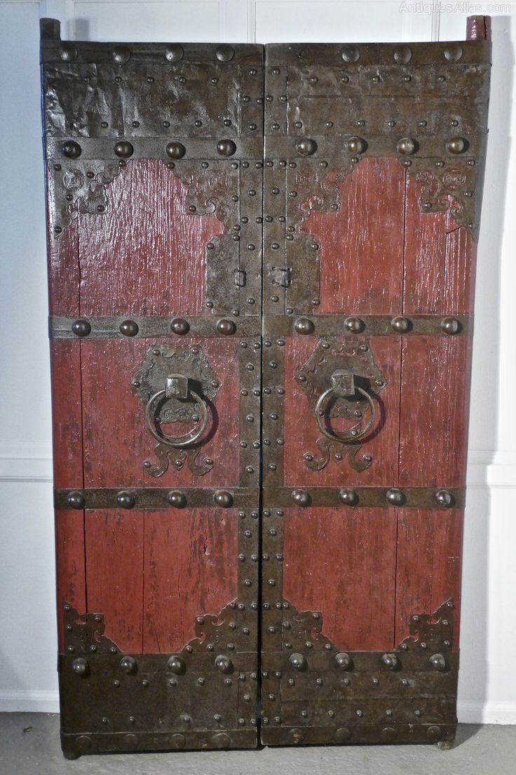 an old wooden door with metal handles and knobs on the front, in a room