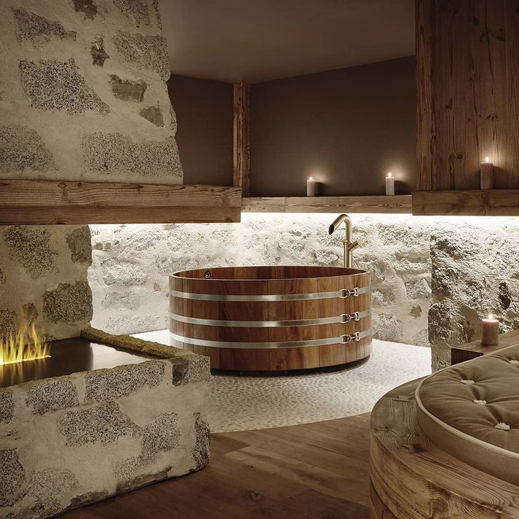 a large wooden tub sitting in the middle of a room next to a stone wall