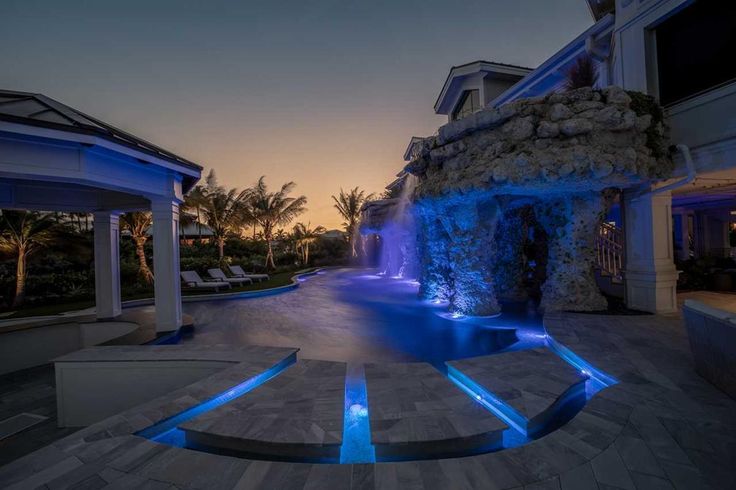 an outdoor swimming pool with blue lights at night