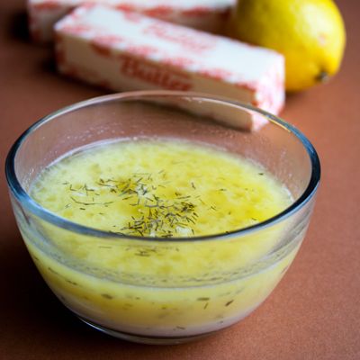 a glass bowl filled with yellow liquid next to lemons and two bars of soap